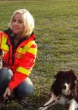 ehrenamtliche Rettungshundeführerin in oranger Einsatzkleidung mit ihrem Hund